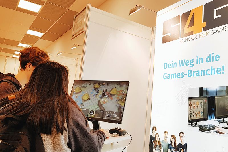 Zwei Interessenten spielen Semesterprojekte am S4G Messestand